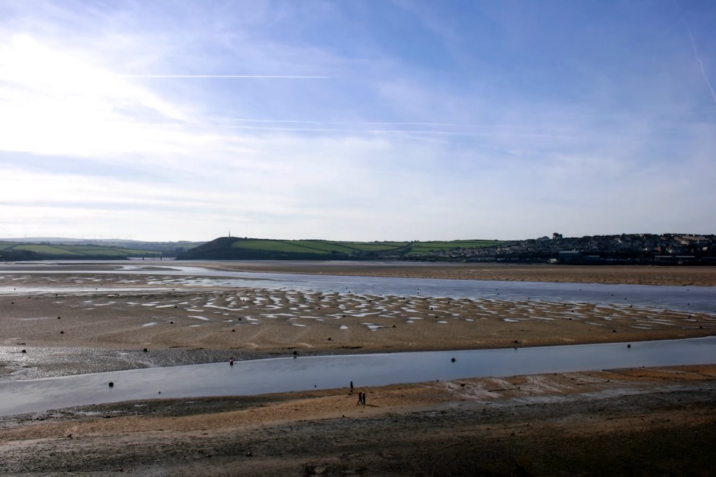 wide shot from above of sandbanks in an estuary, opposite town in far distance