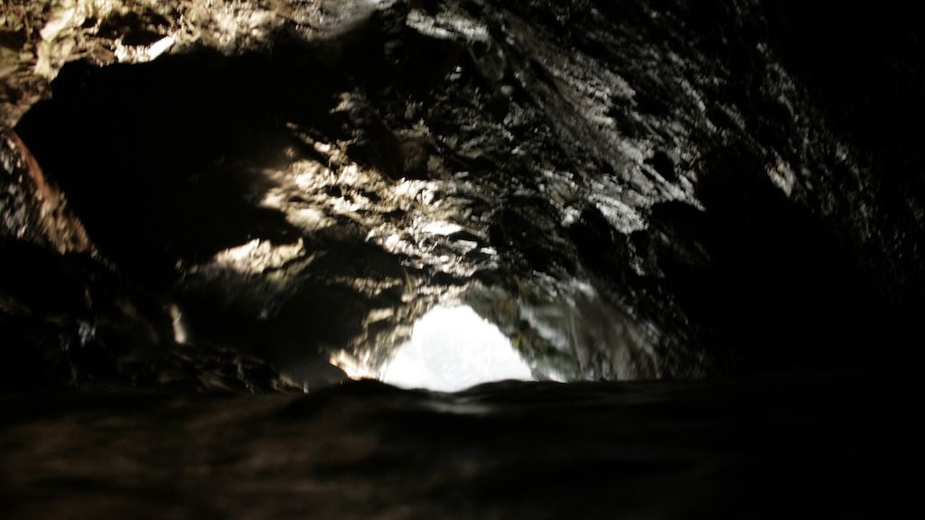 interior sea cave with rising tide, rock ceiling lit from cave mouth arches above the viewer